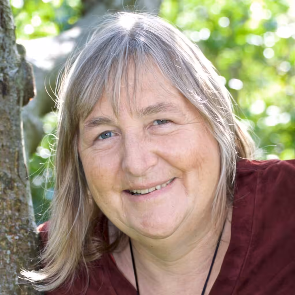 Andrea Sam guckt durch Baumgabelung