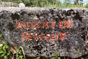 Behauener Stein mit Text in rot